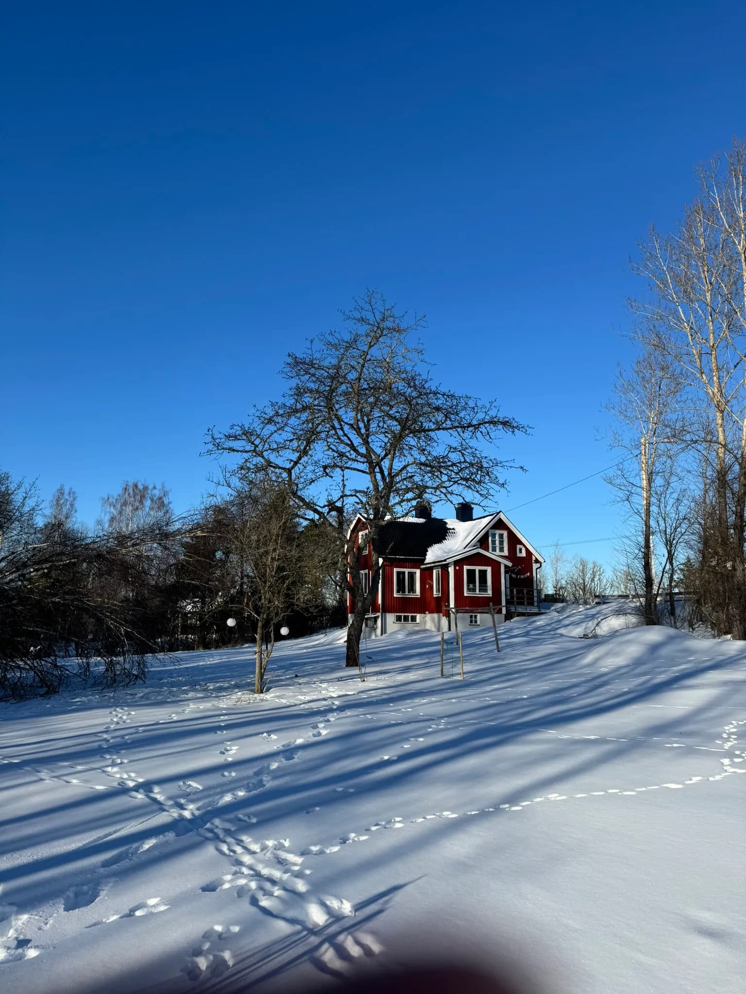 Rotes Schwedenhaus im Schnee unter klarem Winterhimmel