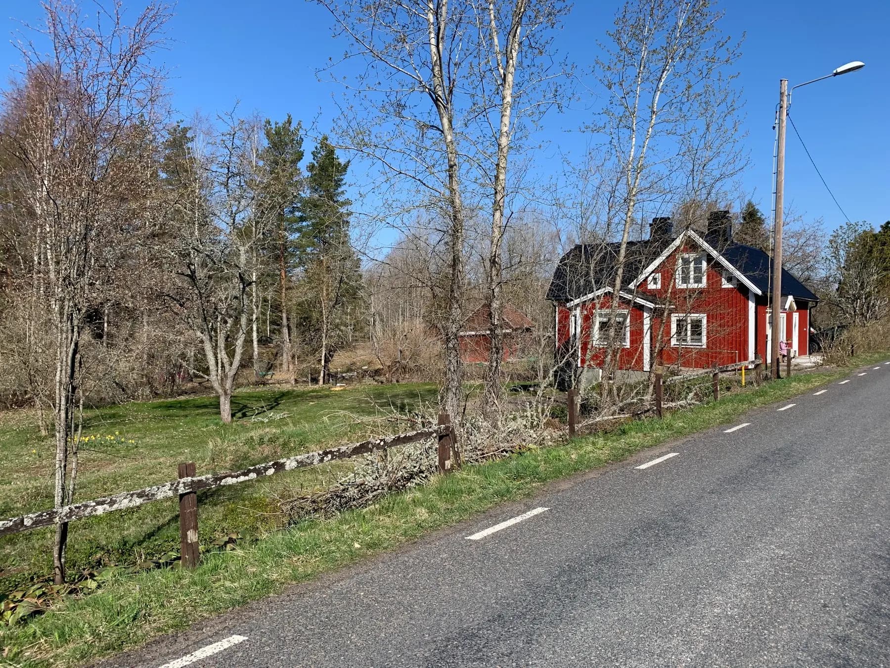 Rotes Holzhaus an der Straße mit kahlen Bäumen im Frühling