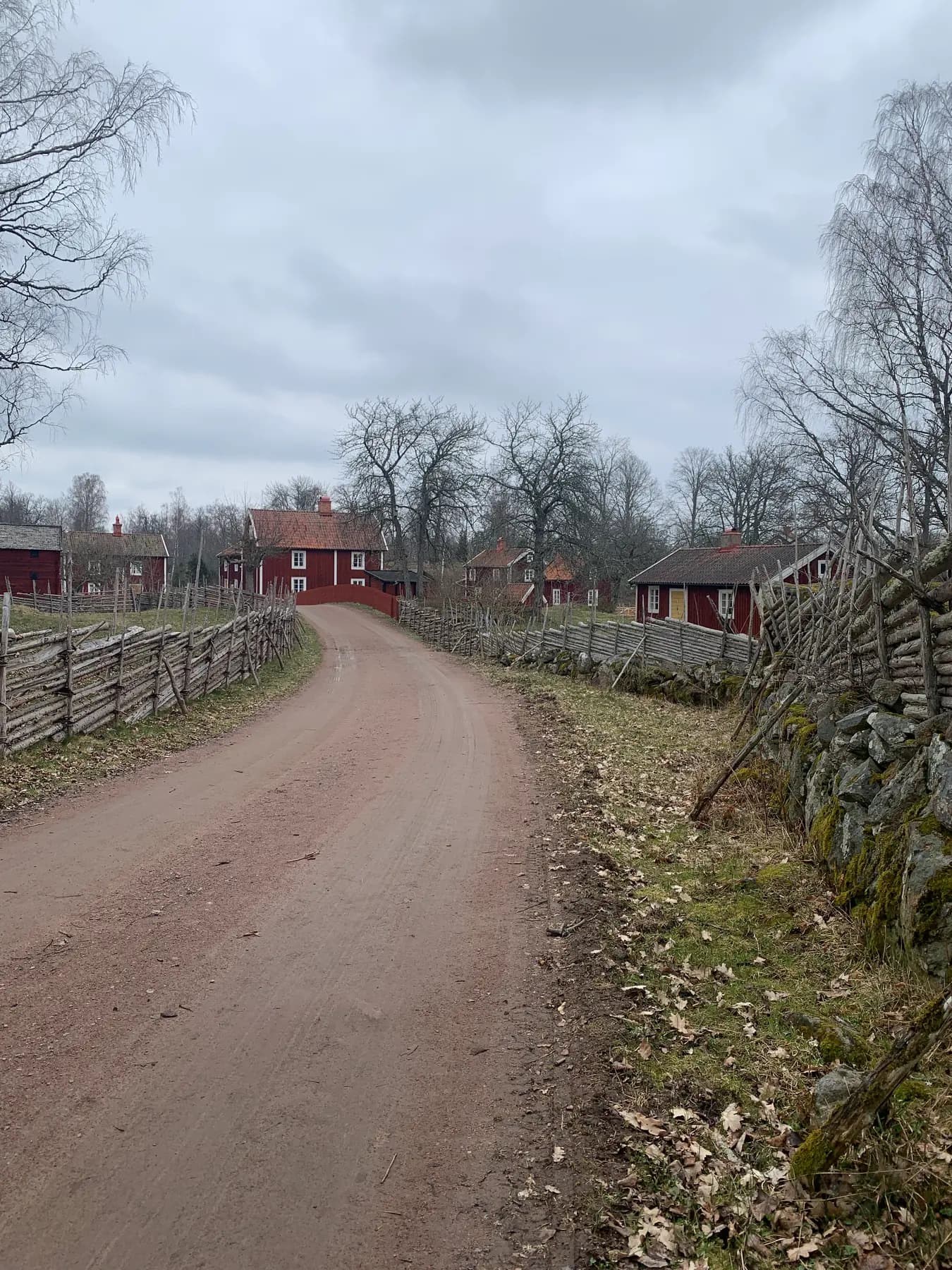 Sandweg mit Holzzäunen zu einem roten Haus in Stensjö by