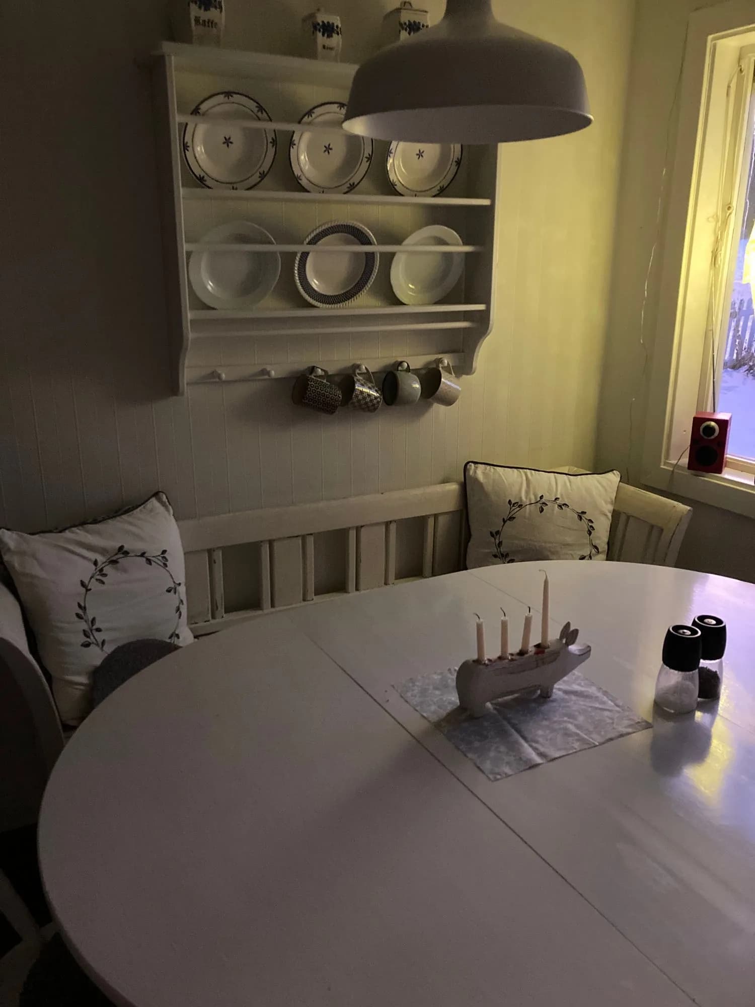 Rund matbord med bänk, tallrikshylla och vinterfönster